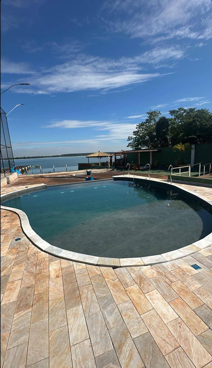 Piscina de borda curva com deck de madeira, à beira de um lago
