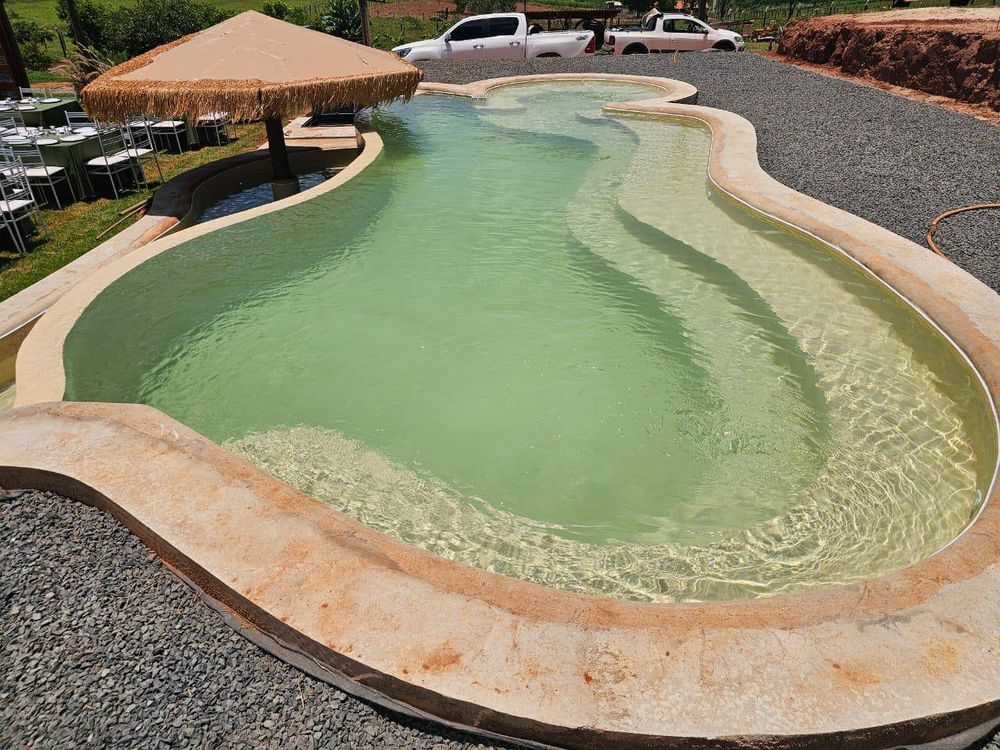 Piscina de forma livre com prainha rasa, revestida com manta armada clara