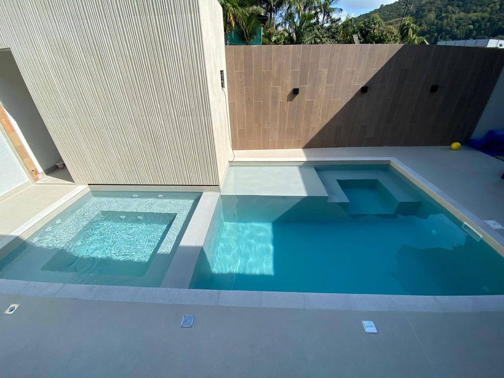 Spa quadrado ao lado da piscina, os dois com manta armada clara